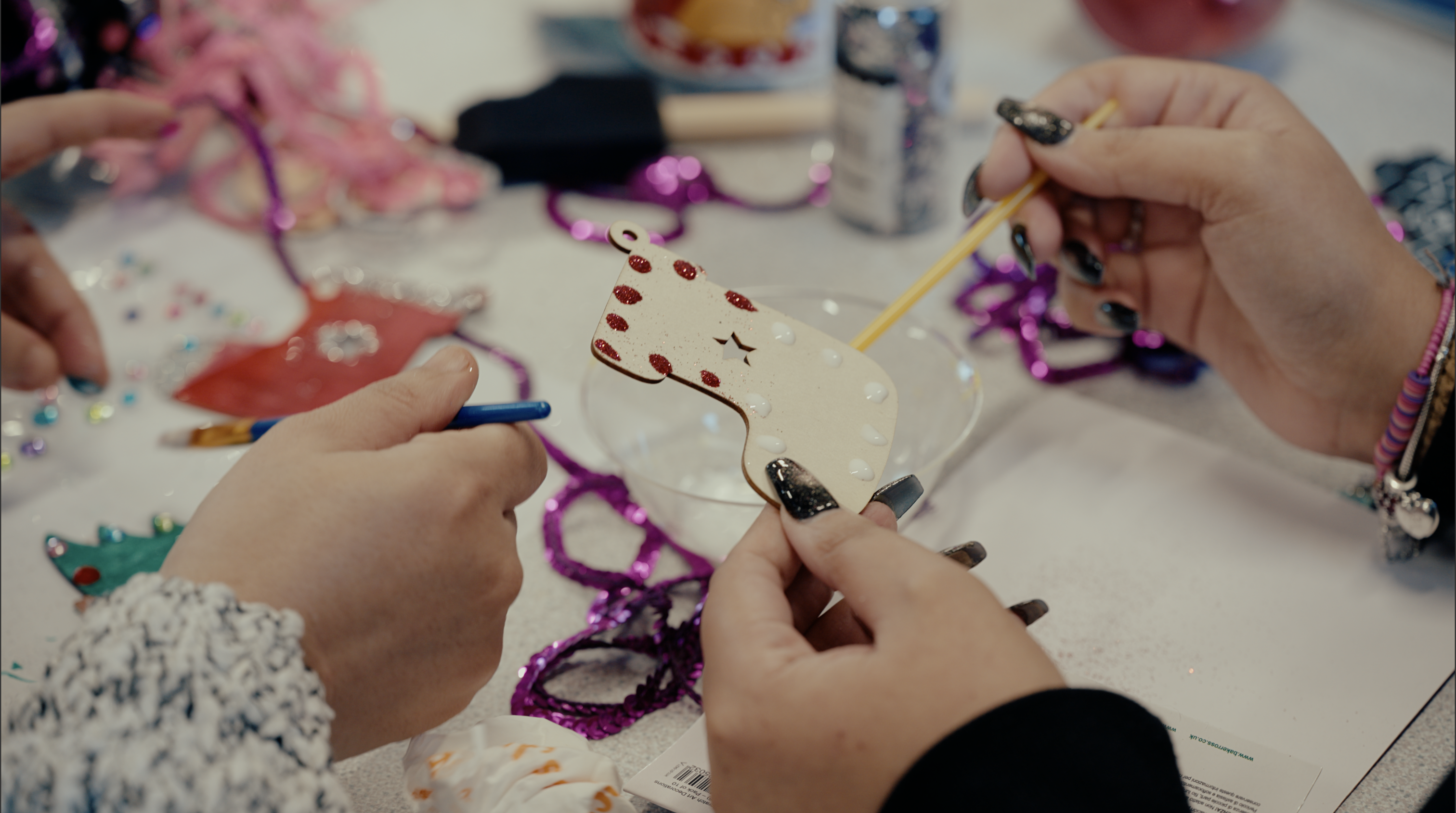 Hands decorating a craft activity at a table